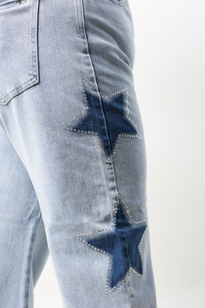 Detalle de estrellas en mezclilla con brillos sobre barrel jeans color azul claro.