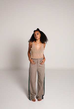 Modelo usando pantalon de vestir beige de pierna amplia con rayas verticales y detalle de franjas verdes.
