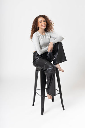 Pantalon de vinipiel negro para mujer en pose sentada con silueta amplia