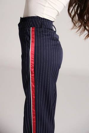 Detalle lateral de pantalon azul marino con rayas verticales y franja roja.