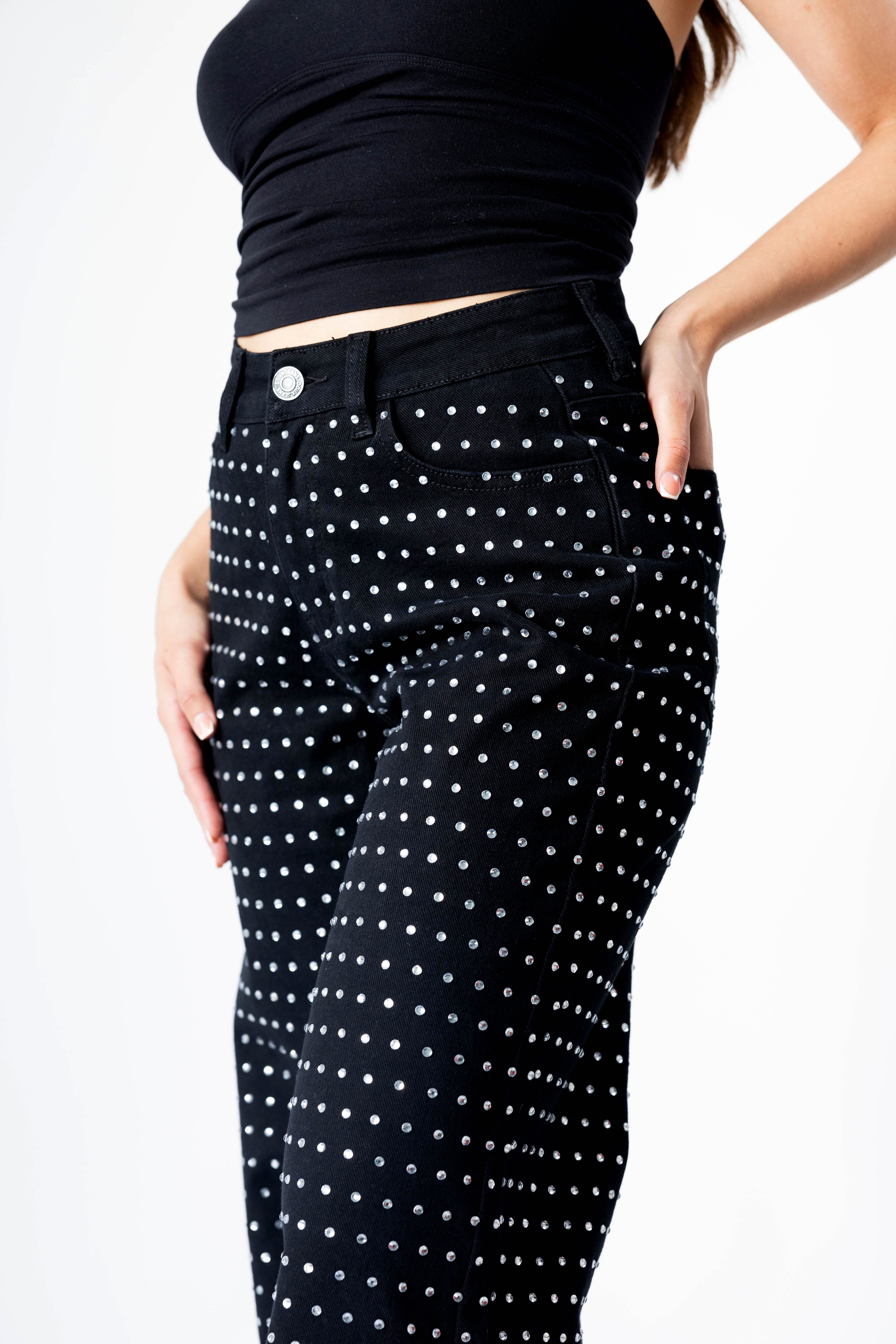 Detalle de pantalón recto negro con brillos en zona de cintura y bolsillos