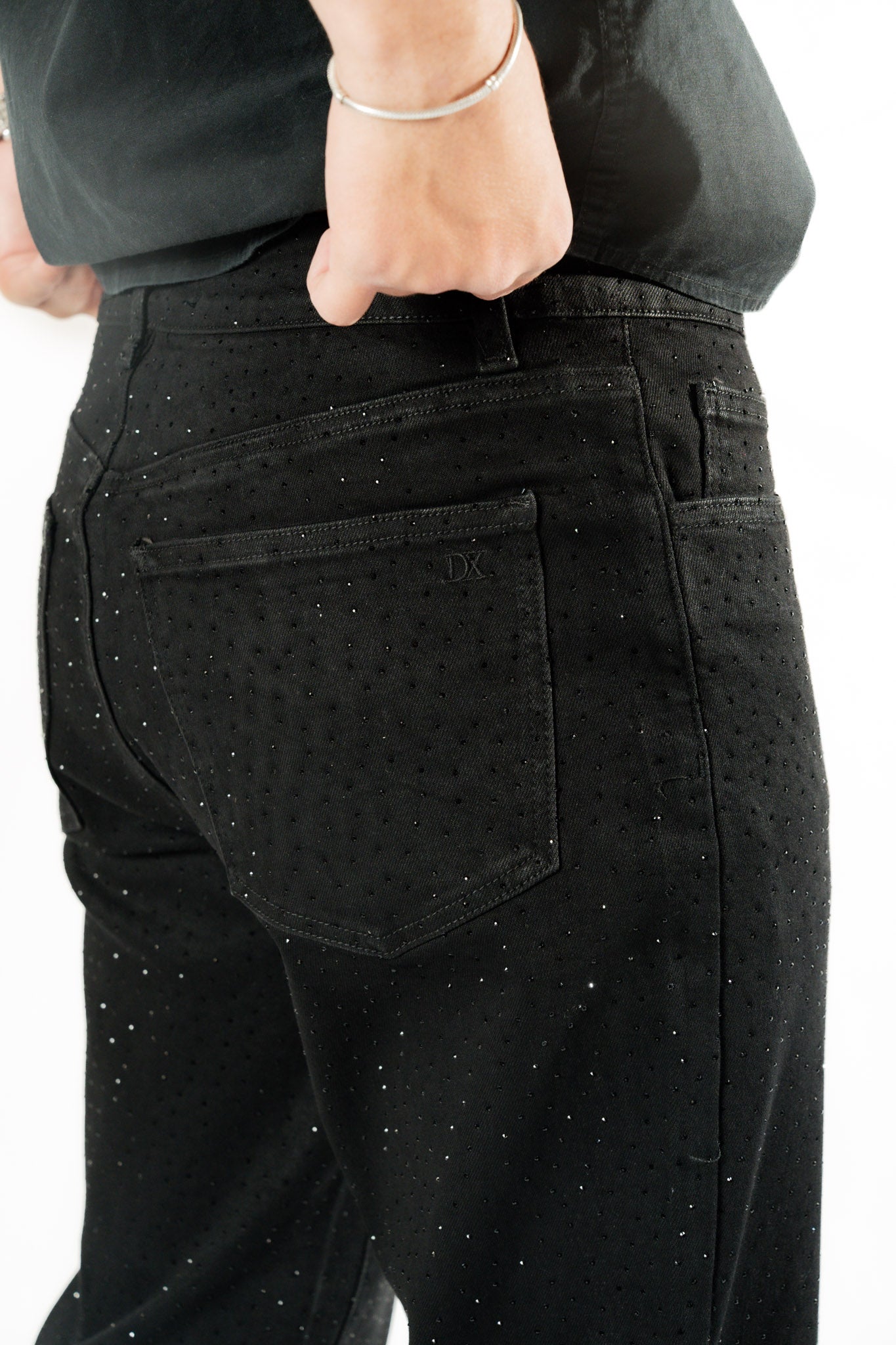 Detalle trasero de pantalon recto negro con brillos sutiles y bolsillo posterior