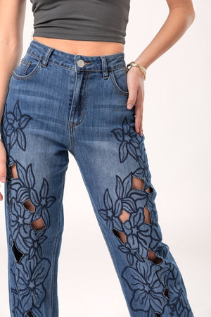 Detalle frontal de pantalon wide leg azul con flores bordadas y aberturas decorativas