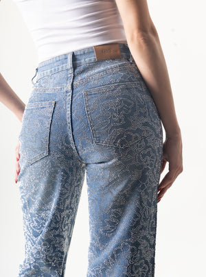 Detalle de pantalon wide leg azul con piedras brillantes sobre mezclilla y bolsillos traseros.