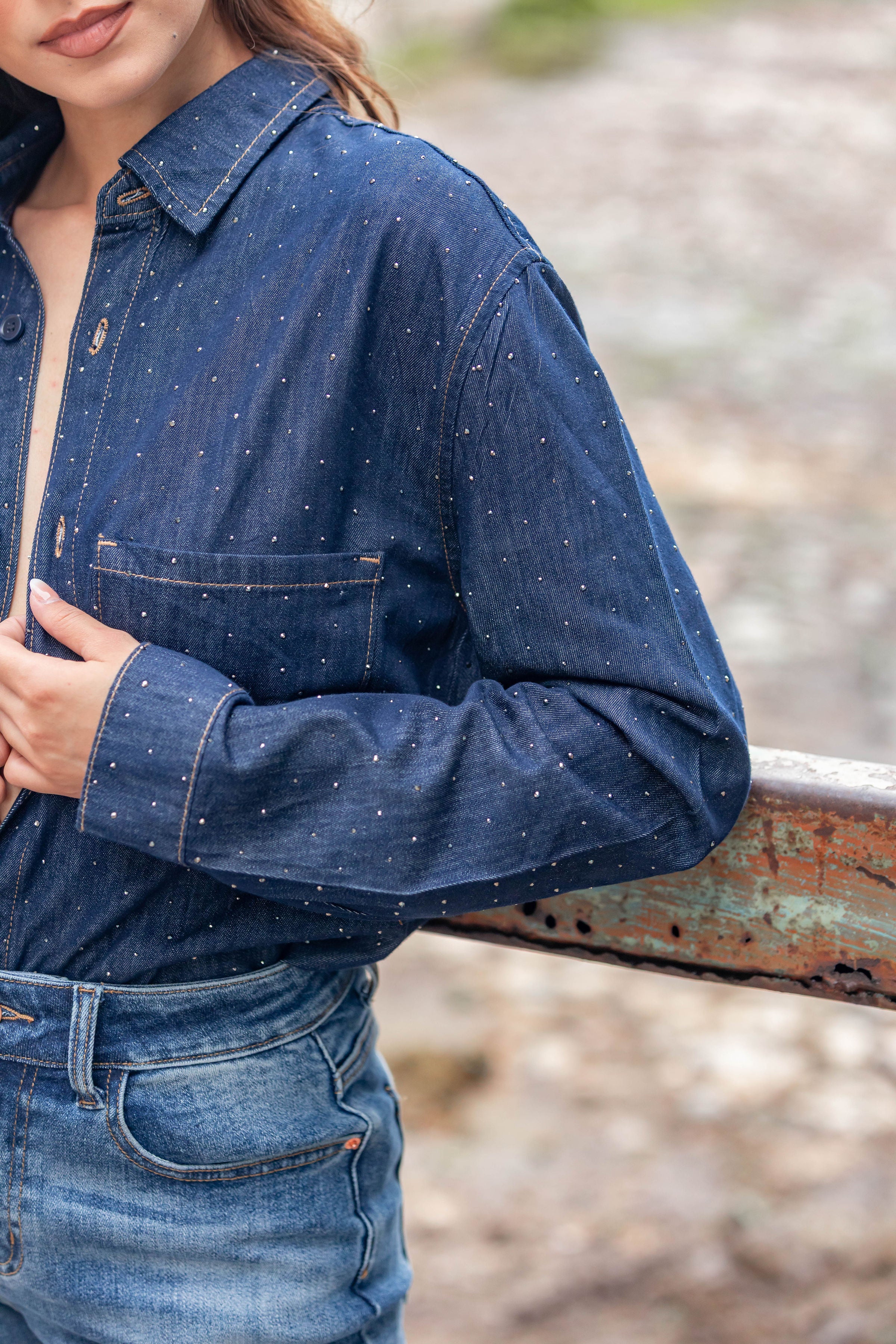 Detalle de camisa de mezclilla azul oscuro para mujer con brillos y bolsillo frontal