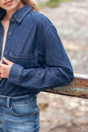 Detalle de camisa de mezclilla azul oscuro para mujer con brillos y bolsillo frontal