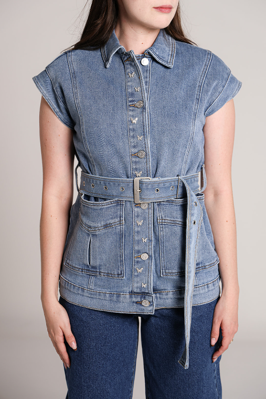 Detalle de chaleco de mezclilla azul para mujer con cinturón y bolsillos frontales.
