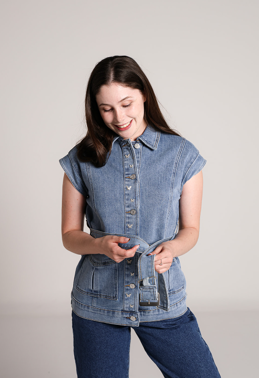 Chaleco de mezclilla azul para mujer con botones, bolsillos y cinturón ajustable.