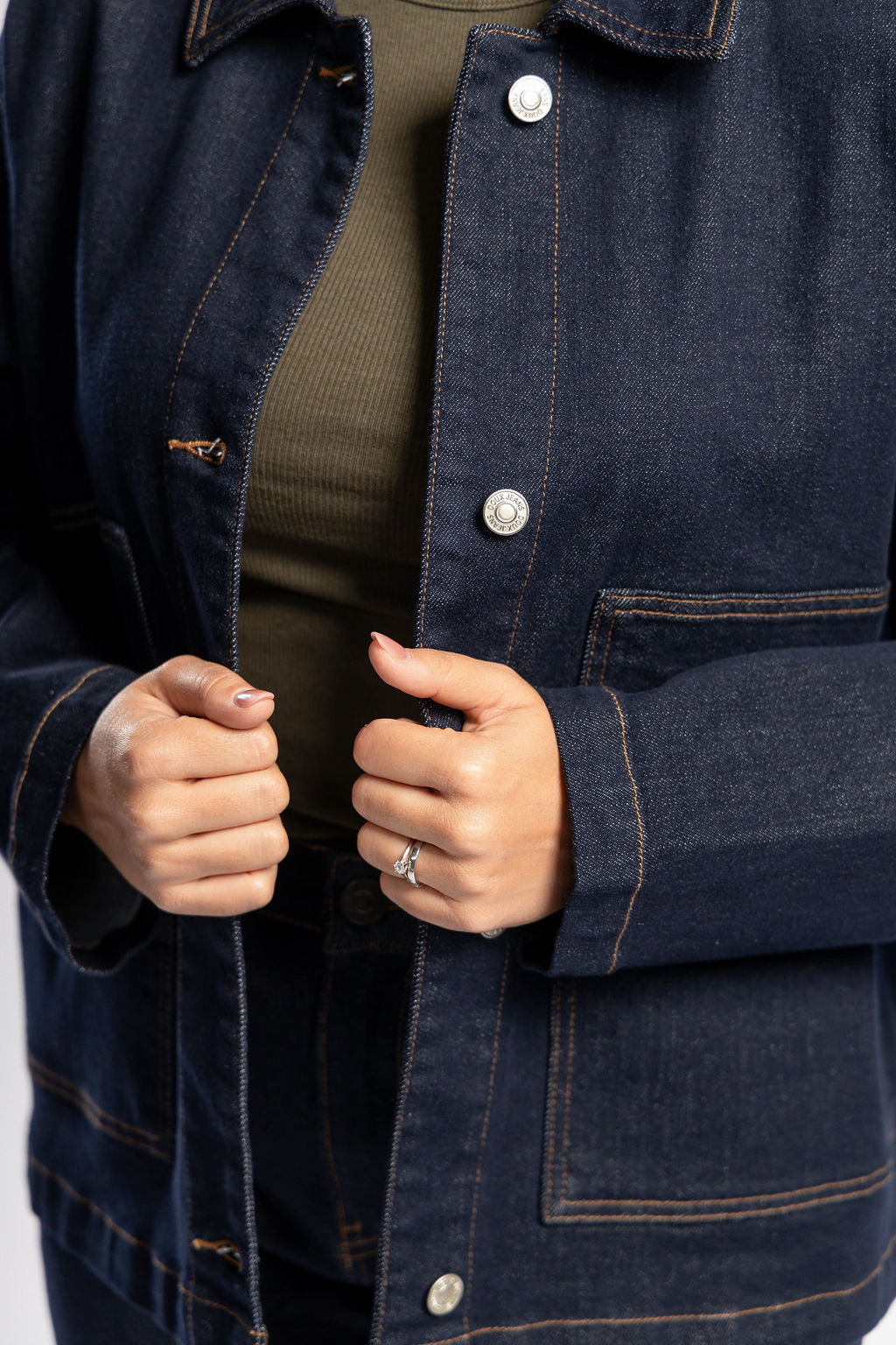 Detalle frontal de chamarra de mezclilla dark blue oversize con bolsas de parche y costuras contrastantes