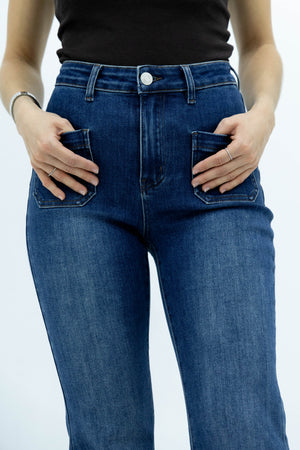 Detalle frontal de pantalon acampanado azul con bolsas de parche y tiro alto