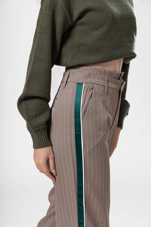 Detalle lateral de pantalon de vestir taupe con líneas verticales y franja verde