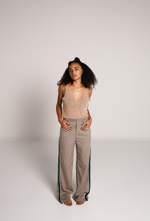 Modelo usando pantalon de vestir beige de pierna amplia con rayas verticales y detalle de franjas verdes.