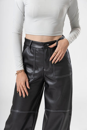 Detalle frontal de pantalon de vinipiel negro con costuras contrastantes