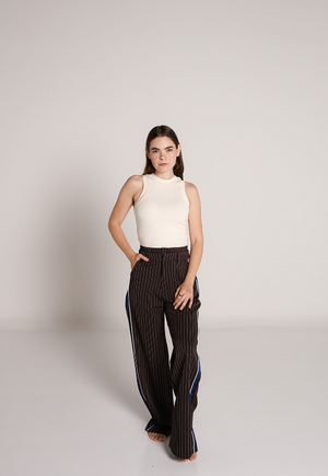 Mujer usando pantalon de vestir chocolate con rayas verticales y detalle lateral azul.