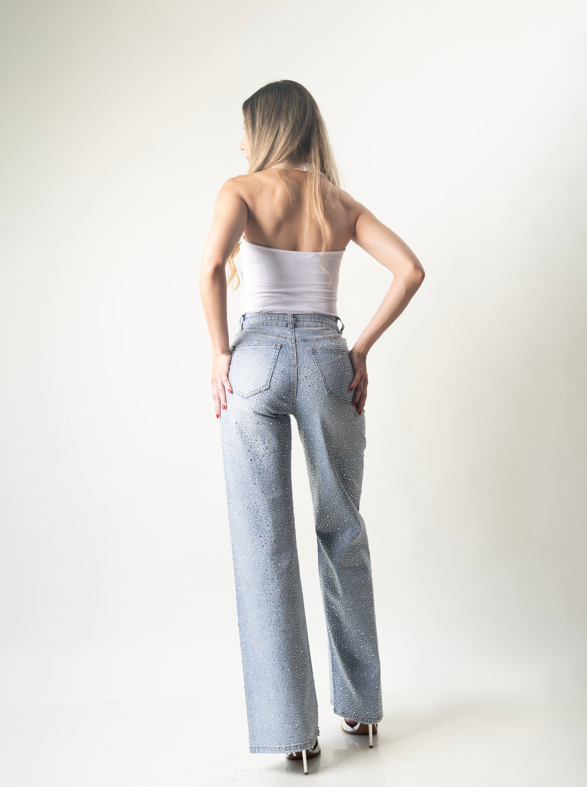 Vista posterior del pantalon wide leg azul con aplicaciones brillantes.