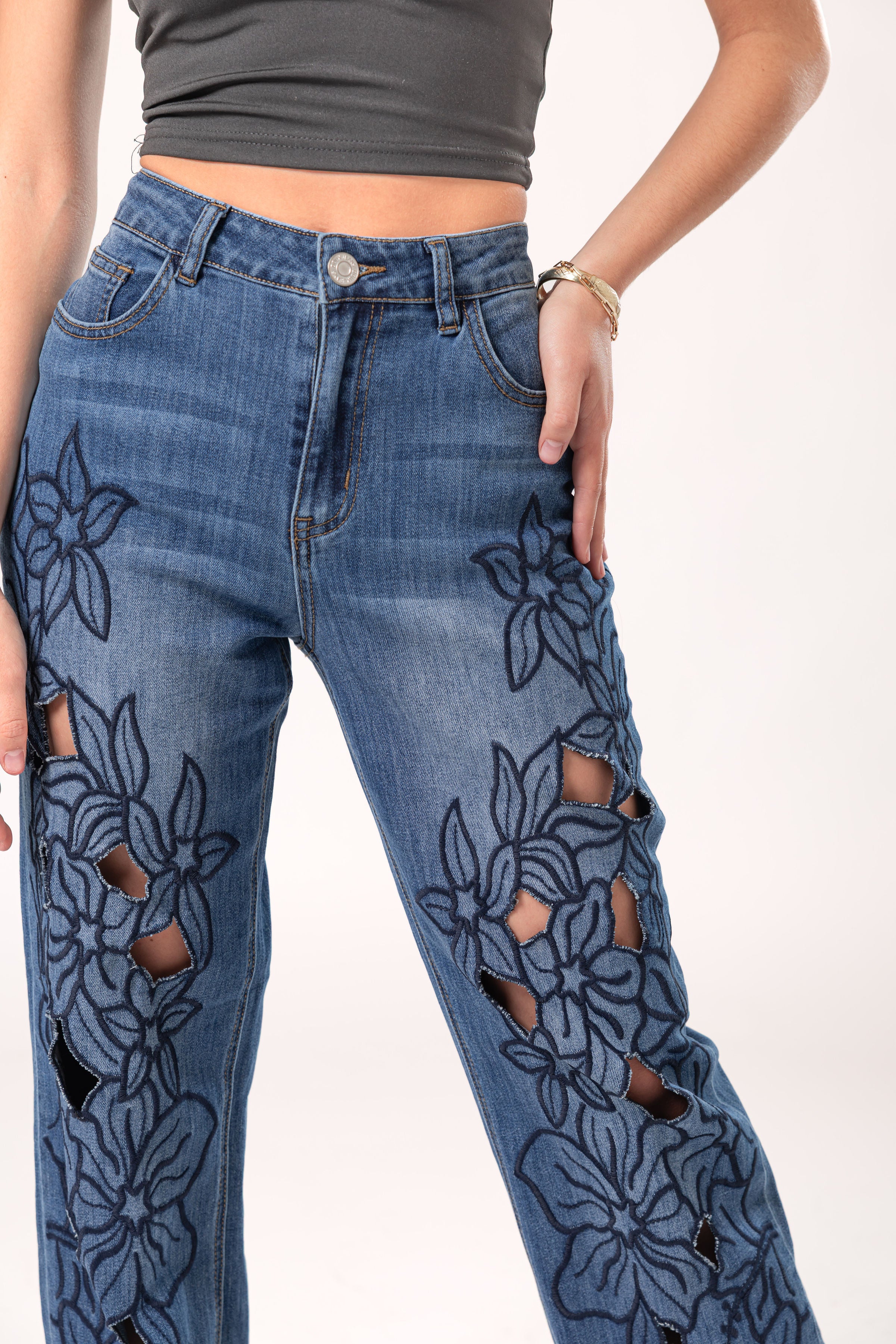 Detalle frontal de pantalon wide leg azul con flores bordadas y aberturas decorativas