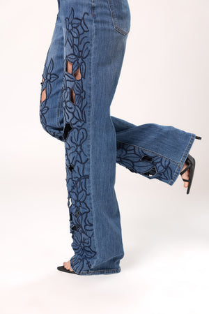 Detalle lateral de pantalon wide leg azul con flores bordadas y aberturas en mezclilla