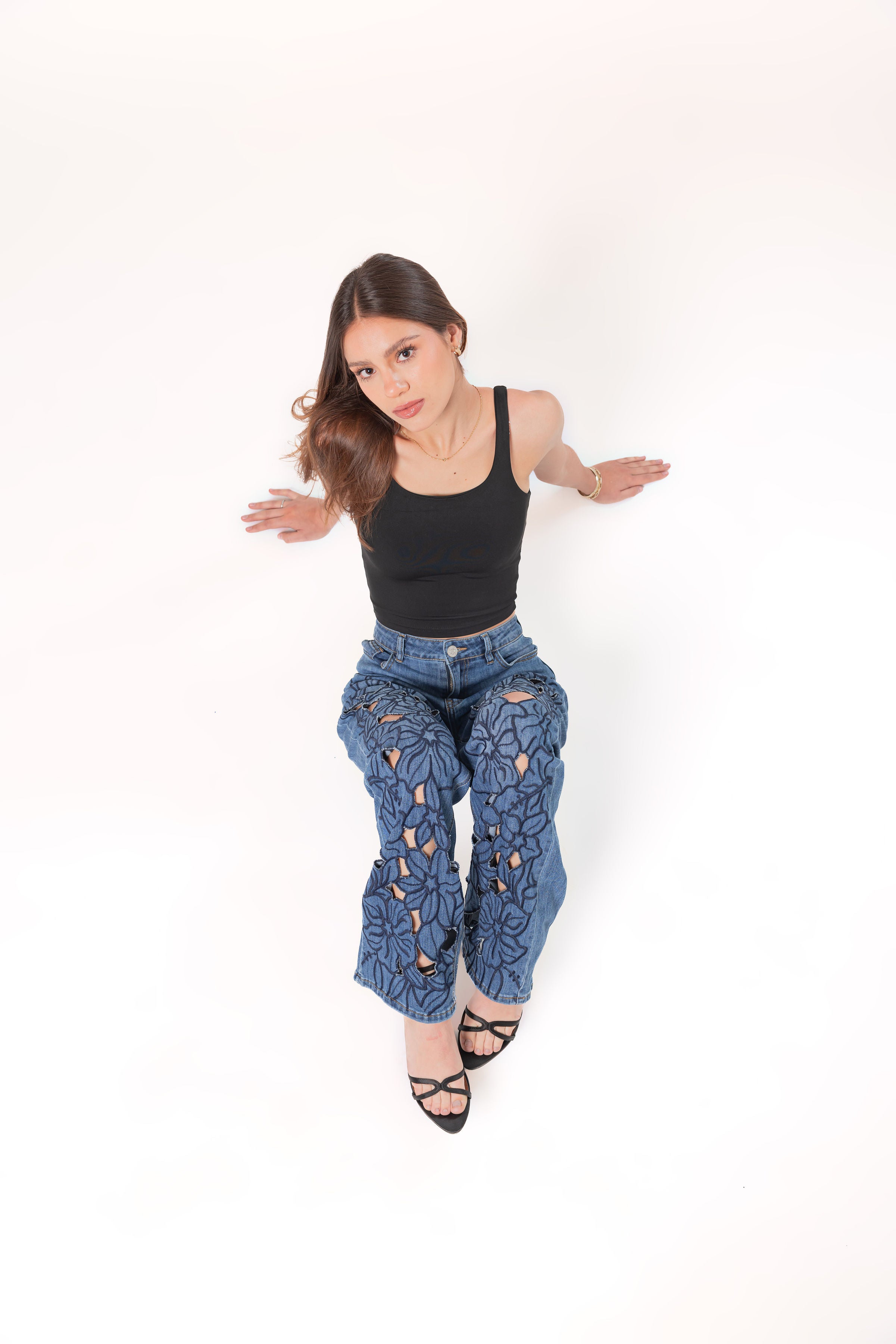 Pantalon wide leg de mezclilla azul con bordados florales y silueta amplia en pose sentada