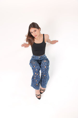 Pantalon wide leg de mezclilla azul con bordados florales y silueta amplia en pose sentada
