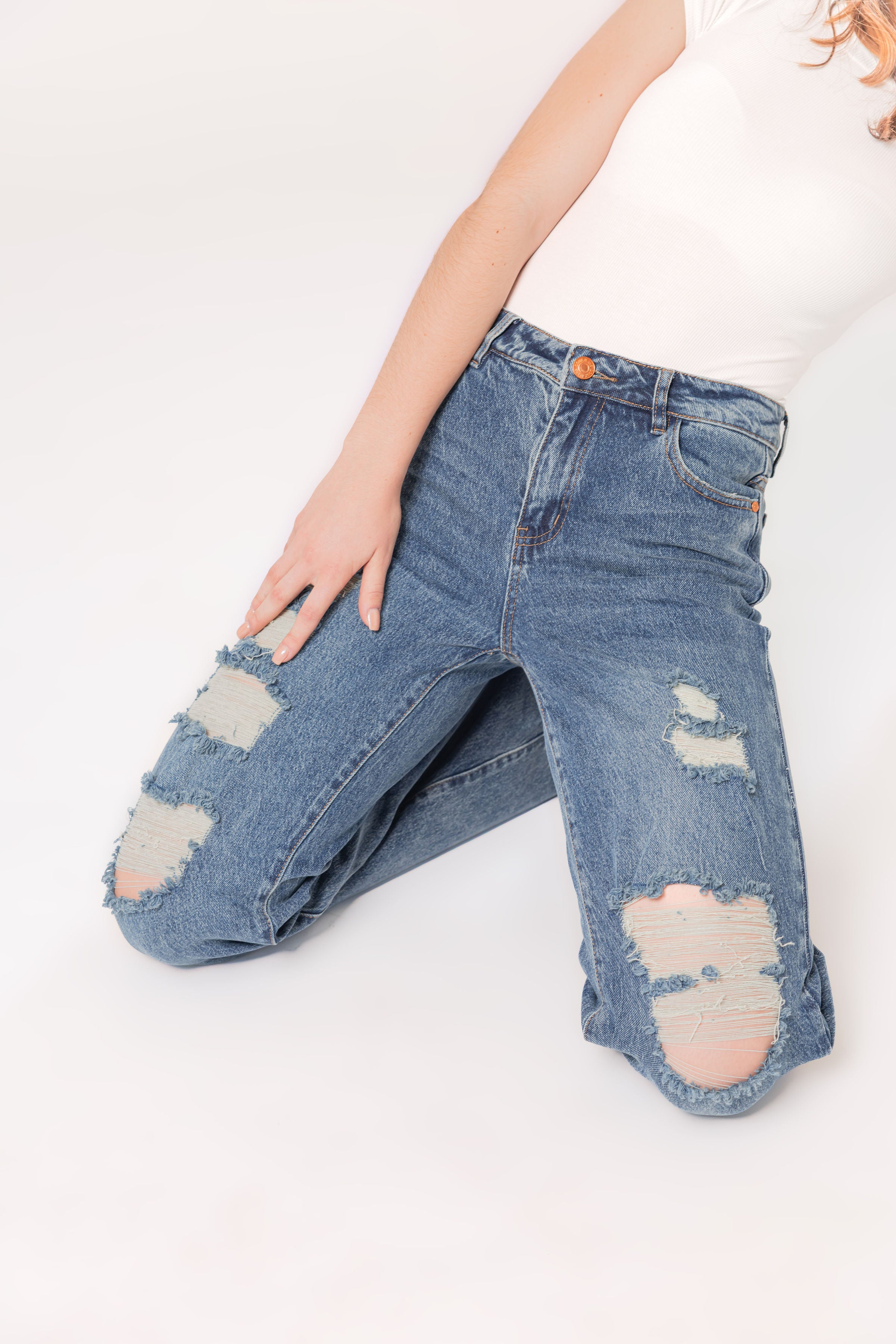 Detalle frontal de pantalon wide leg azul con acabado destroyed y tiro alto