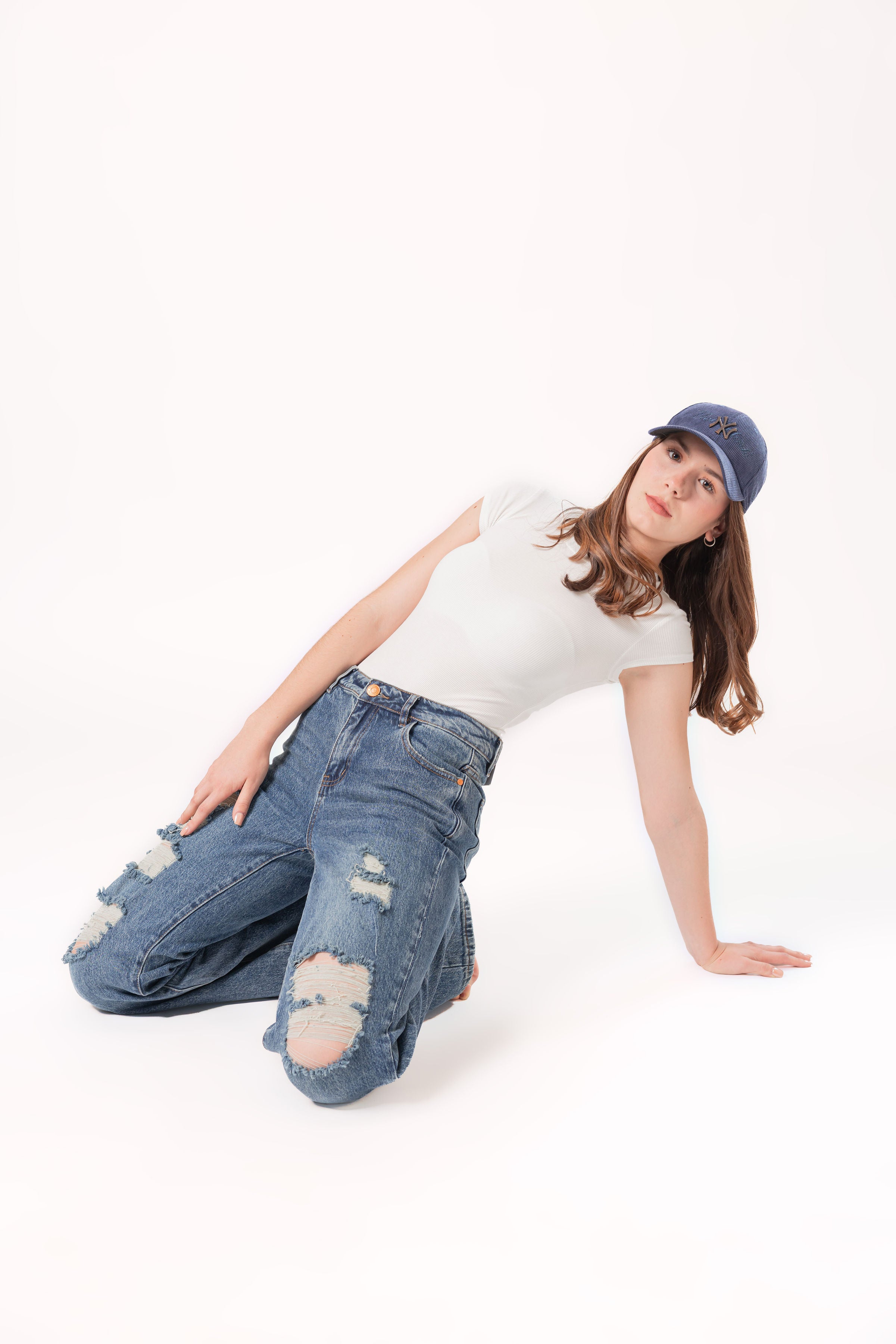 Modelo usando pantalon wide leg destroyed azul en pose lateral sobre fondo blanco