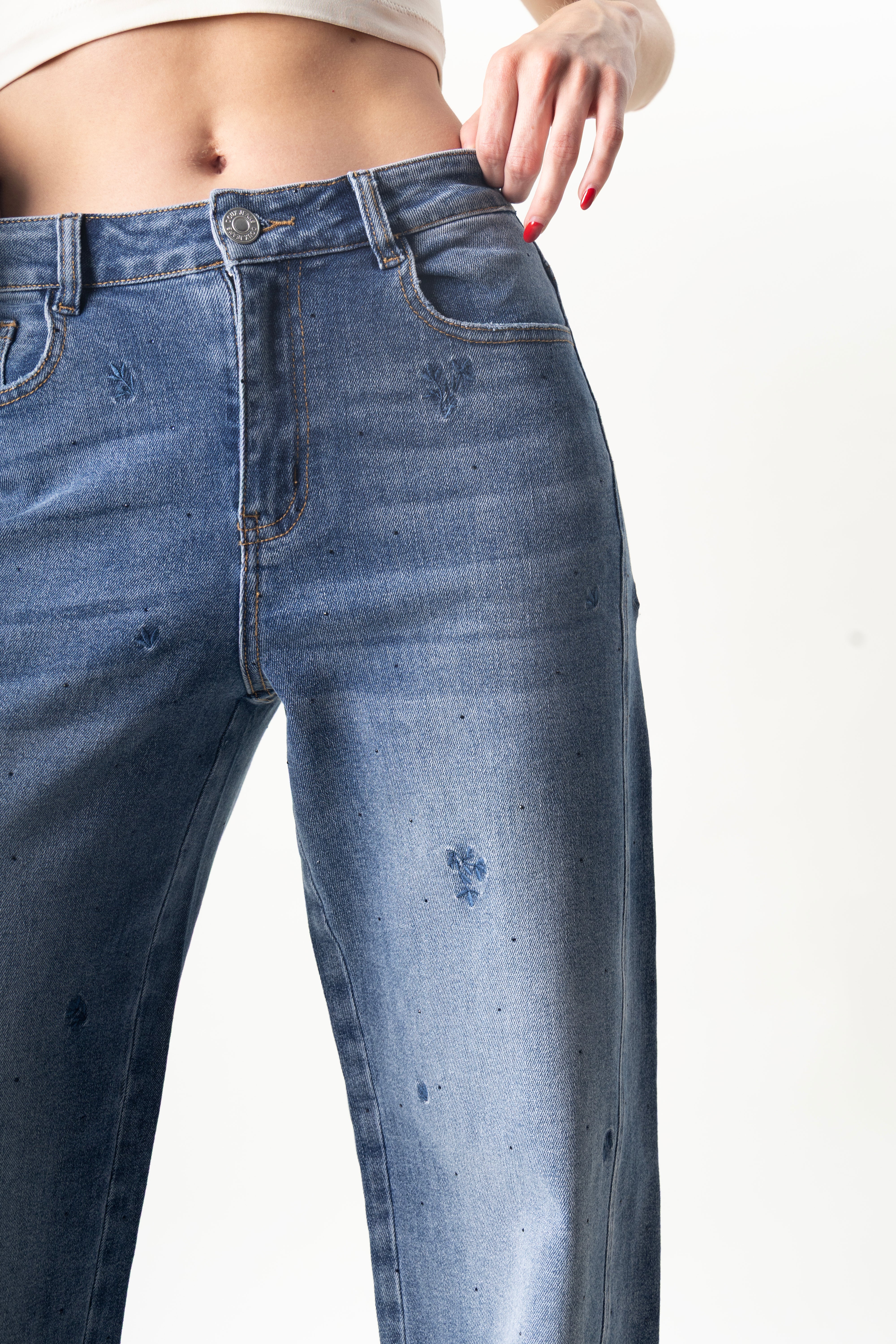 Detalle de pantalon wide leg azul con flores bordadas y brillos dispersos en mezclilla