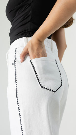 Detalle de bolsillo con bordado negro en pantalon blanco